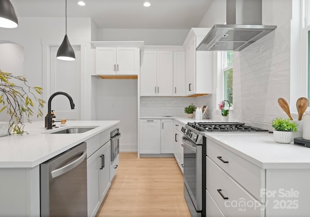 1912 St John St, Charlotte, NC 28216 - kitchen with stainless steel appliances, wall chimney exhaust hood, backsplash, light wood-style flooring, and light countertops