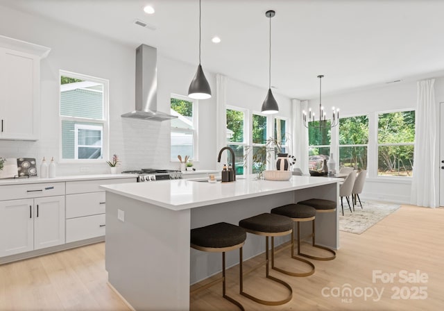 1912 St John St, Charlotte, NC 28216 - kitchen featuring wall chimney range hood, decorative backsplash, healthy amount of natural light, light wood-style floors, and recessed lighting