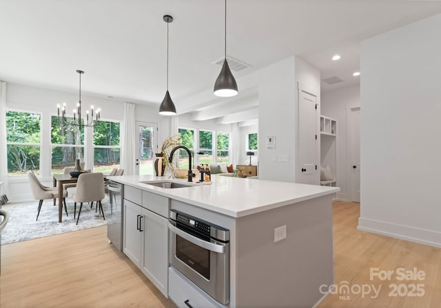 1912 St John St, Charlotte, NC 28216 - kitchen with light wood finished floors, a chandelier, recessed lighting, stainless steel appliances, and light countertops