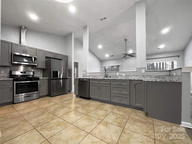 kitchen with high vaulted ceiling, sink, gray cabinetry, light stone counters, and stainless steel appliances