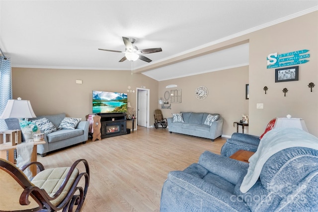 living area featuring light wood finished floors, a warm lit fireplace, lofted ceiling, ceiling fan, and crown molding