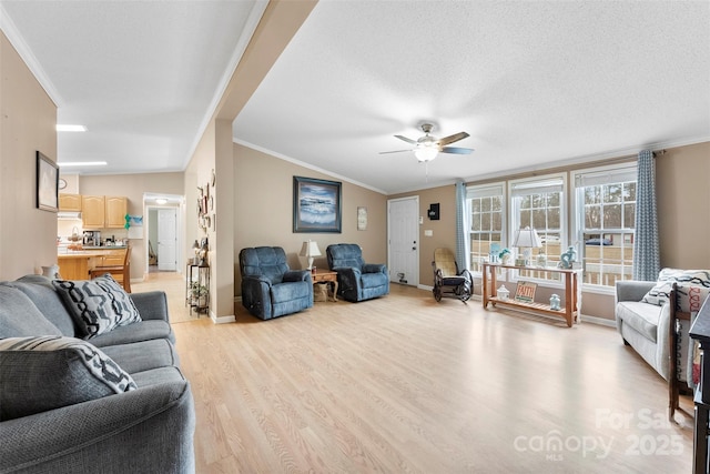 living room featuring ornamental molding, ceiling fan, a textured ceiling, light wood-type flooring, and baseboards