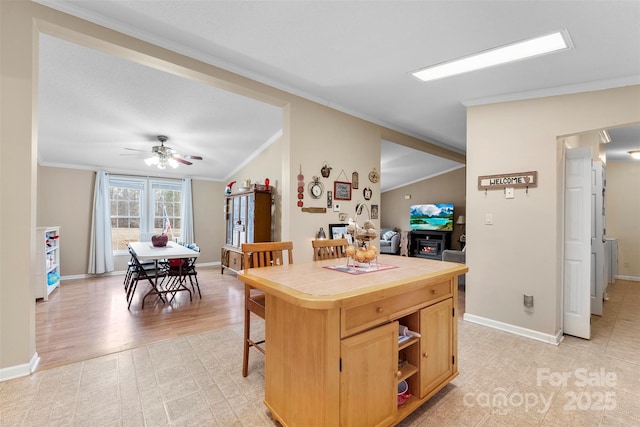 kitchen featuring tile countertops, open shelves, ornamental molding, light brown cabinets, and baseboards