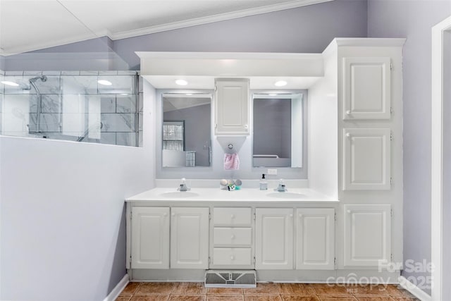 bathroom with crown molding, a tile shower, a sink, and double vanity