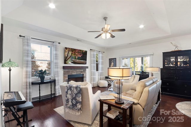 living room featuring ceiling fan, dark hardwood / wood-style flooring, a fireplace, and a raised ceiling