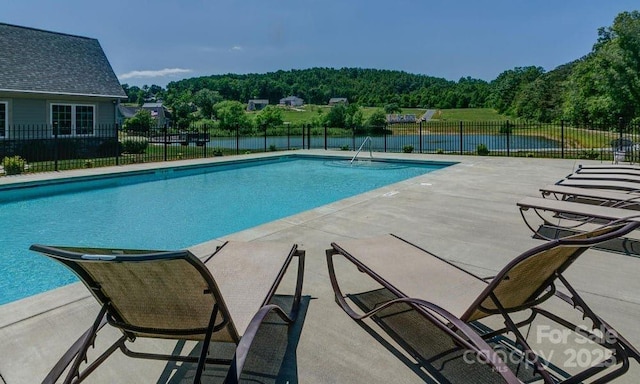 view of swimming pool featuring a water view and a patio area