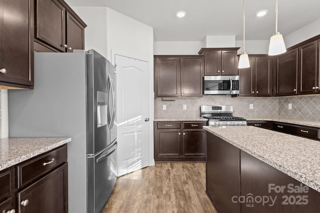 kitchen with decorative light fixtures, dark brown cabinets, light hardwood / wood-style floors, and appliances with stainless steel finishes