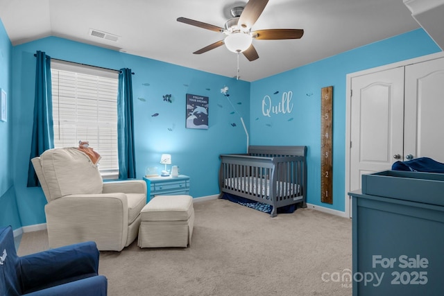 bedroom with vaulted ceiling, light colored carpet, a nursery area, and ceiling fan