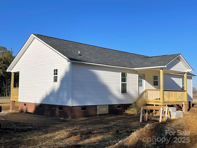 view of side of home with roof with shingles, crawl space, and a wooden deck