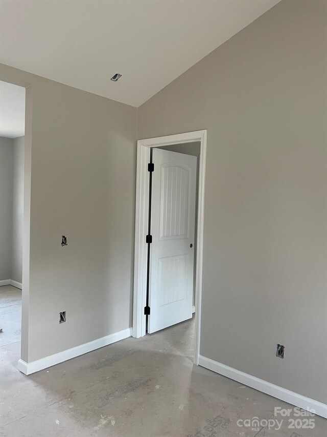 spare room with baseboards, vaulted ceiling, and concrete flooring