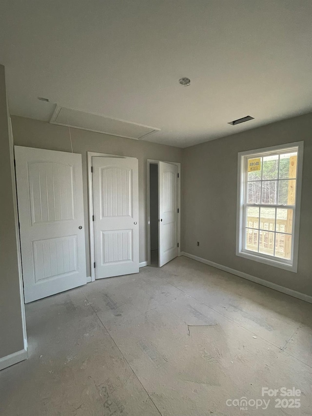 unfurnished bedroom with visible vents, attic access, and baseboards