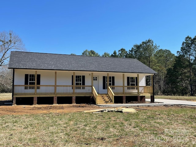 view of front of home with covered porch, a front lawn, and a shingled roof