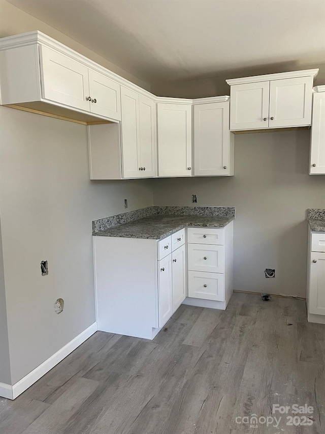 kitchen featuring light wood-type flooring, white cabinets, and baseboards