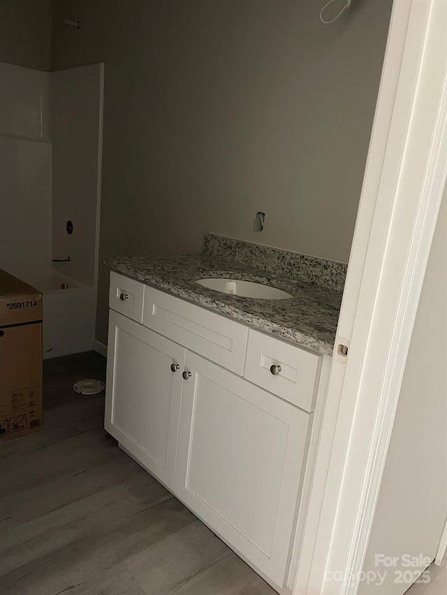 bathroom featuring tub / shower combination, wood finished floors, and vanity