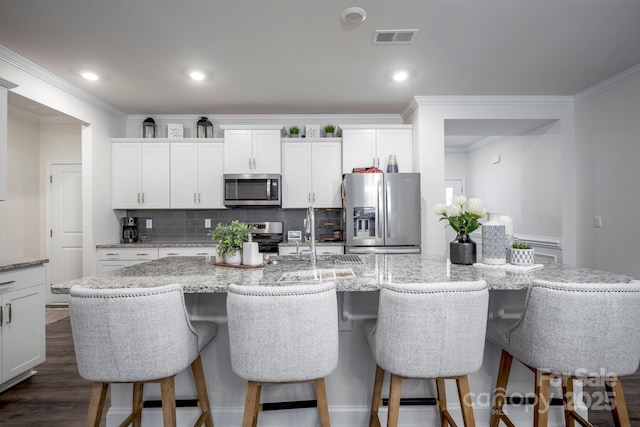 kitchen featuring white cabinetry, appliances with stainless steel finishes, and a center island with sink