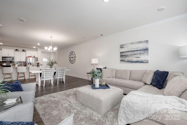 living area with a chandelier, dark wood finished floors, baseboards, ornamental molding, and recessed lighting
