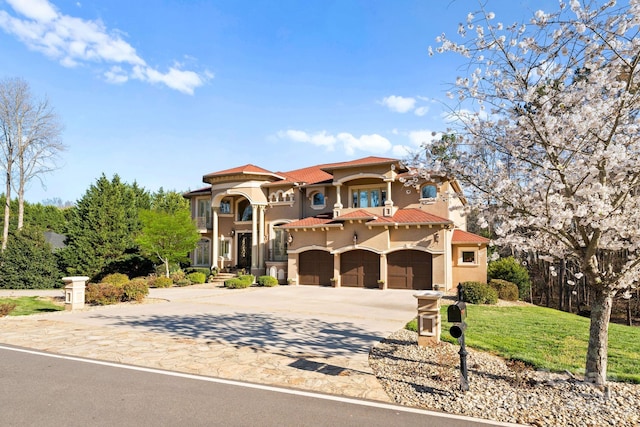 mediterranean / spanish-style house featuring a front yard, stucco siding, concrete driveway, a garage, and a tiled roof