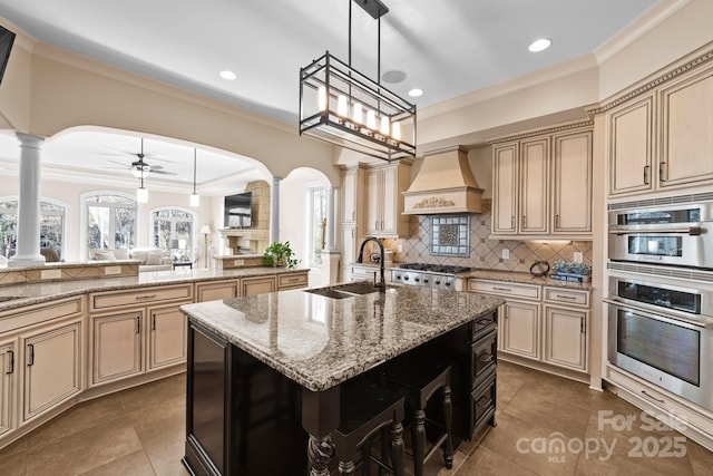 kitchen featuring cream cabinetry, custom range hood, and a sink