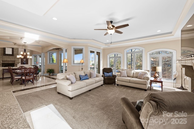 living room featuring a tray ceiling, decorative columns, a fireplace, and recessed lighting