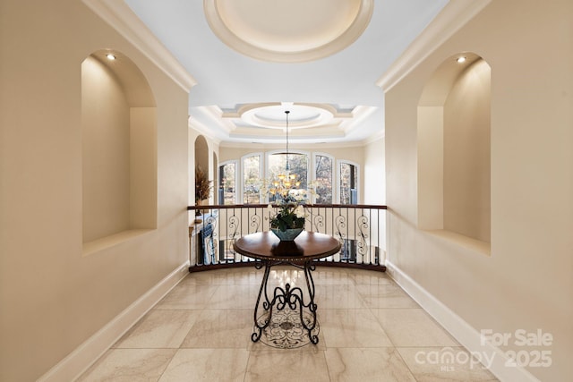 hallway with baseboards, a raised ceiling, a chandelier, and crown molding