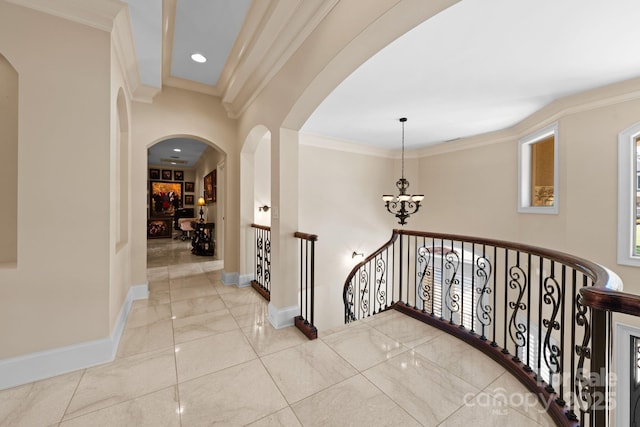 hall with an upstairs landing, a notable chandelier, ornamental molding, arched walkways, and baseboards