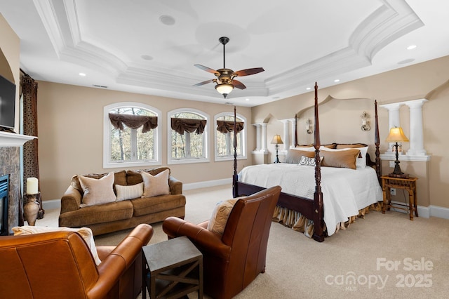 bedroom featuring a tray ceiling, ornamental molding, light colored carpet, and a tile fireplace