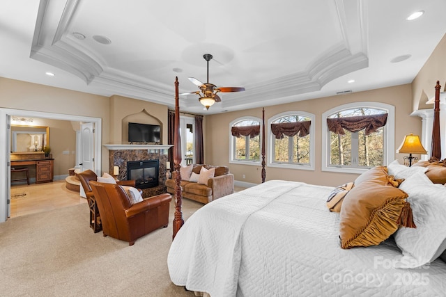 bedroom with a tray ceiling, crown molding, and a high end fireplace