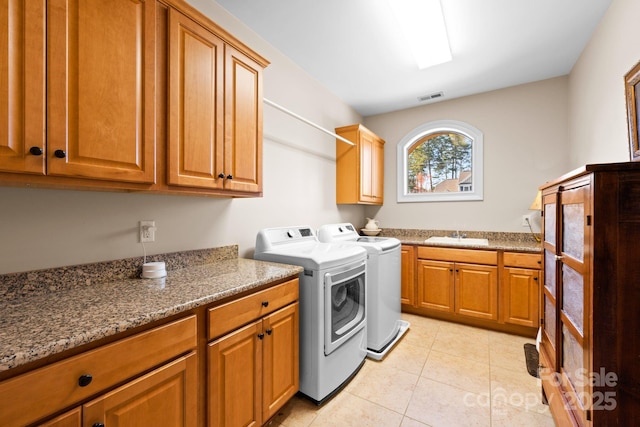 laundry room with visible vents, a sink, cabinet space, light tile patterned floors, and washing machine and clothes dryer