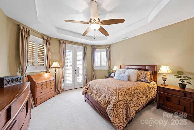 bedroom with visible vents, access to outside, a tray ceiling, french doors, and light colored carpet