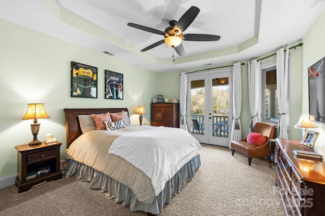 carpeted bedroom featuring access to exterior, visible vents, french doors, a raised ceiling, and a ceiling fan