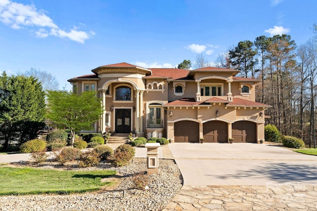 mediterranean / spanish home featuring a tile roof, concrete driveway, stucco siding, french doors, and a garage