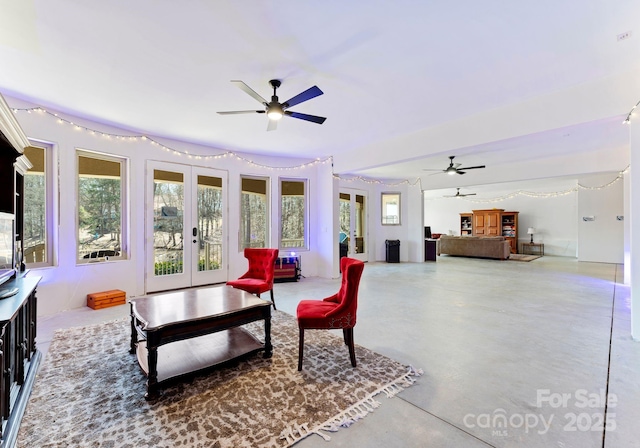 living area featuring french doors, concrete flooring, and a ceiling fan