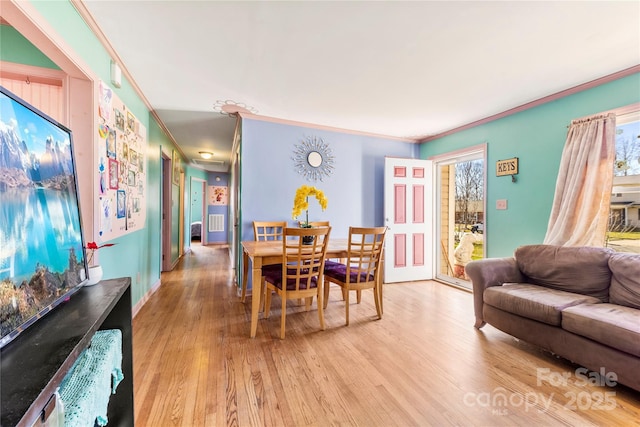 dining area with plenty of natural light, ornamental molding, and light wood-type flooring