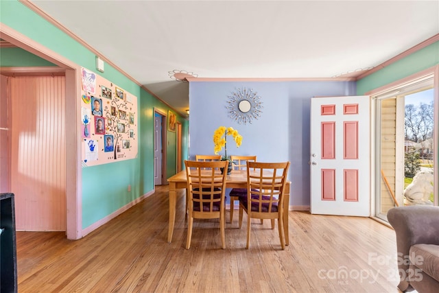 dining area with crown molding and light hardwood / wood-style floors