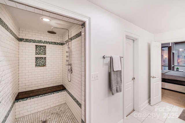 ensuite bathroom featuring connected bathroom, baseboards, tiled shower, and tile patterned flooring