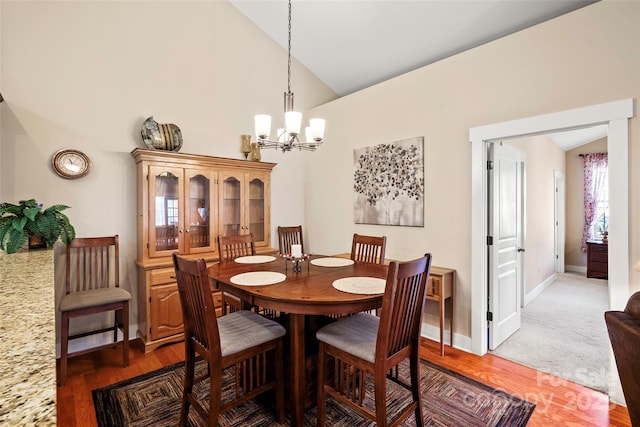 dining space with an inviting chandelier, dark hardwood / wood-style flooring, and high vaulted ceiling