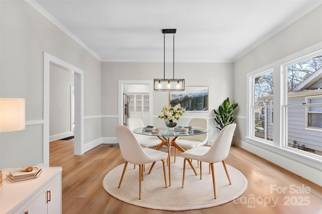 dining space featuring crown molding and light hardwood / wood-style flooring