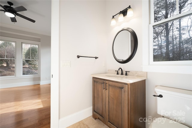 bathroom featuring hardwood / wood-style flooring, vanity, ornamental molding, ceiling fan, and toilet