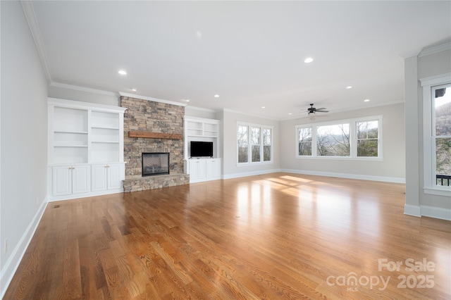 unfurnished living room with a stone fireplace, ornamental molding, ceiling fan, and light wood-type flooring