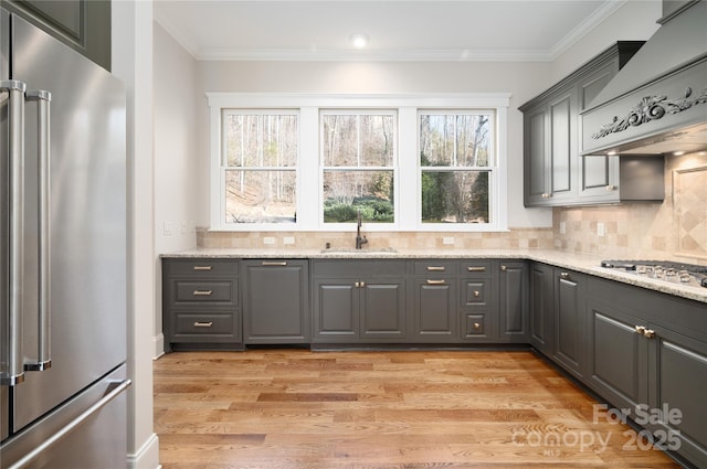 kitchen featuring sink, gray cabinets, appliances with stainless steel finishes, light stone counters, and custom range hood