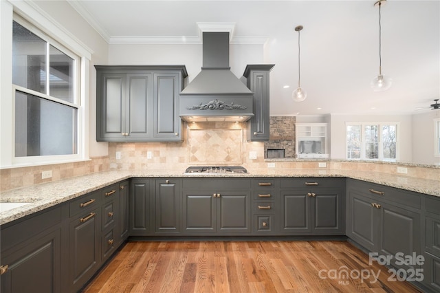 kitchen featuring premium range hood, light stone counters, tasteful backsplash, decorative light fixtures, and stainless steel gas stovetop