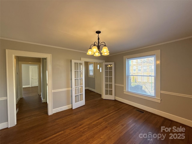 unfurnished dining area featuring crown molding, dark hardwood / wood-style floors, french doors, and a notable chandelier