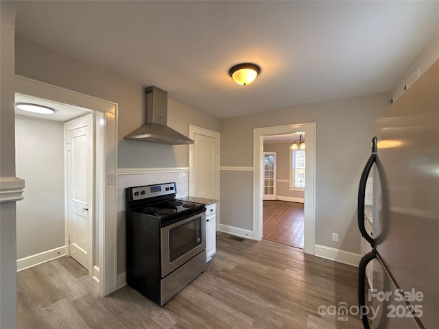 kitchen featuring decorative backsplash, stainless steel appliances, wood-type flooring, and wall chimney range hood