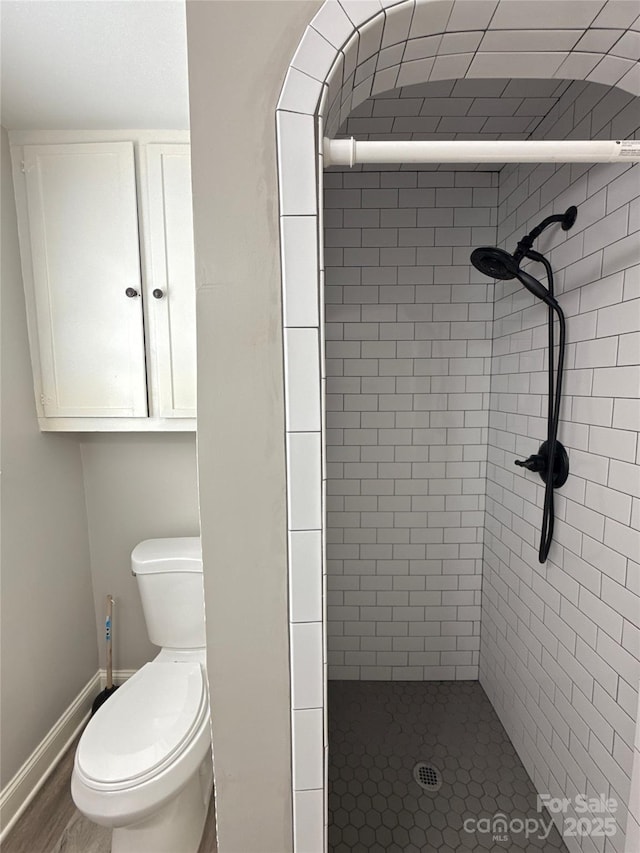 bathroom featuring wood-type flooring, tiled shower, and toilet