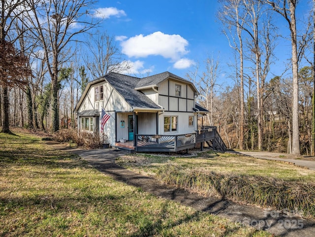 tudor home with a front yard and a deck