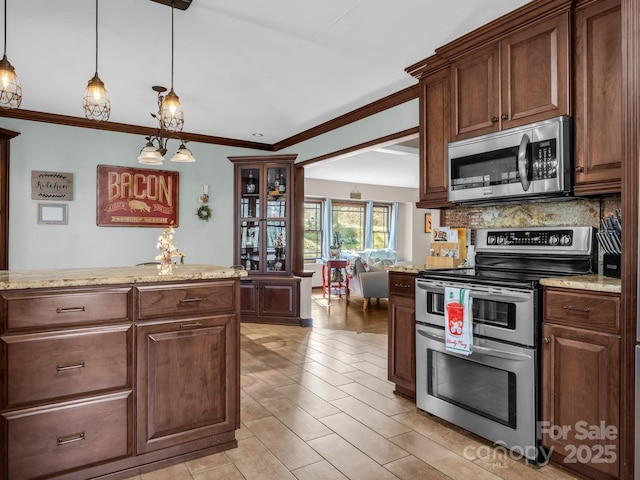 kitchen featuring stainless steel appliances, light stone countertops, ornamental molding, decorative backsplash, and decorative light fixtures