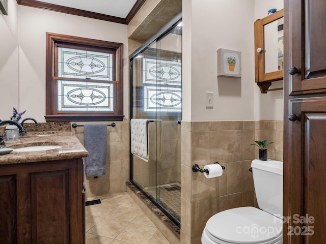 bathroom with toilet, a shower with shower door, crown molding, tile walls, and vanity