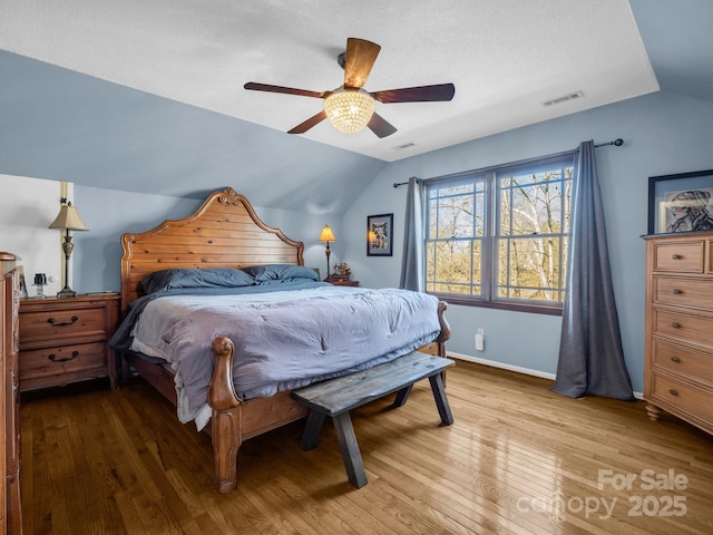 bedroom with vaulted ceiling, wood-type flooring, a textured ceiling, and ceiling fan