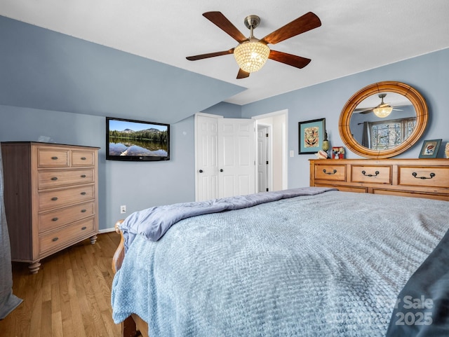 bedroom featuring light hardwood / wood-style flooring, ceiling fan, and vaulted ceiling