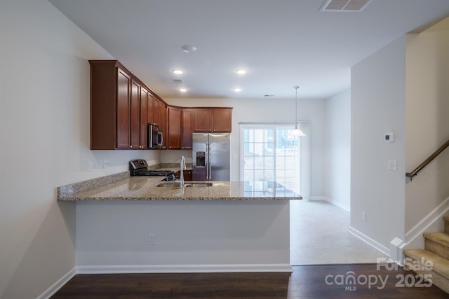 kitchen featuring appliances with stainless steel finishes, decorative light fixtures, sink, kitchen peninsula, and light stone countertops